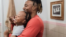 un papa et son enfant se brossent les dents en riant