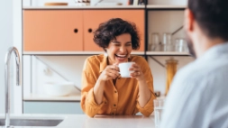 une femme boit un café en riant