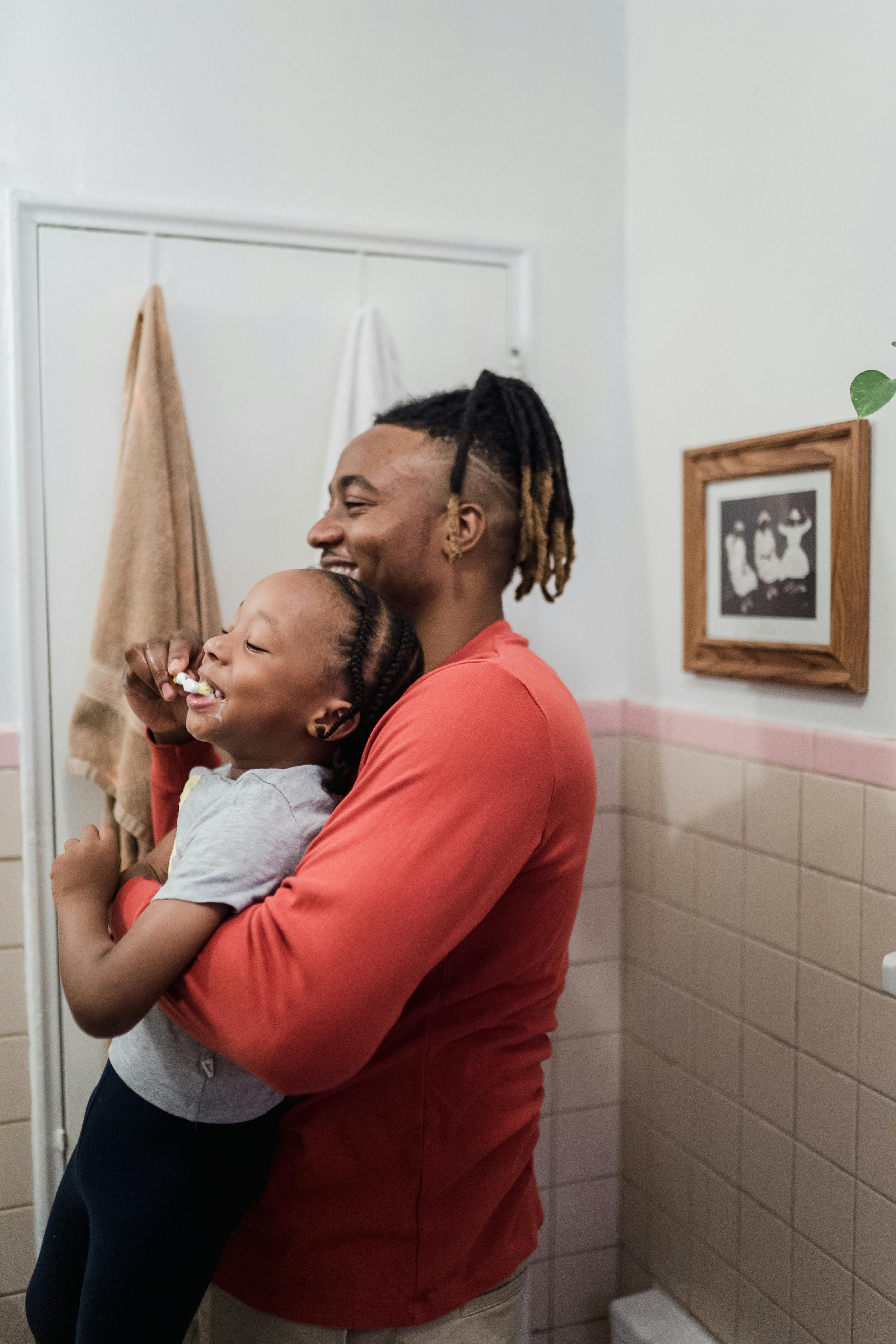 un papa et son enfant se brossent les dents en riant